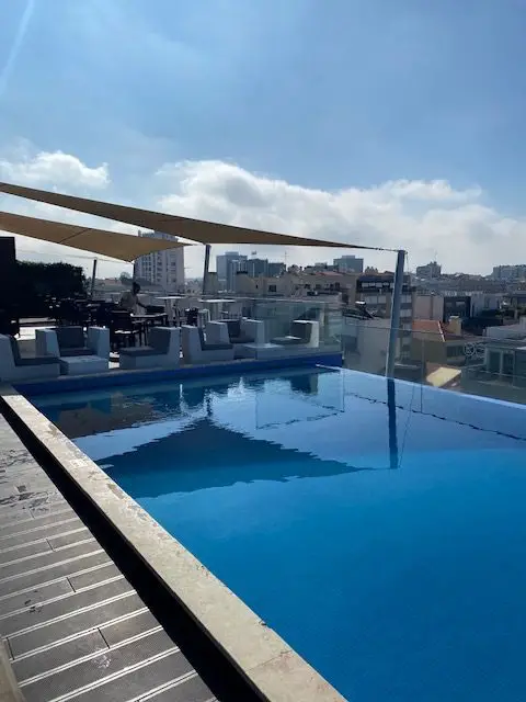 The larger of  Hotel Jupiter Lisbon's rooftop pools, with awnings for shade