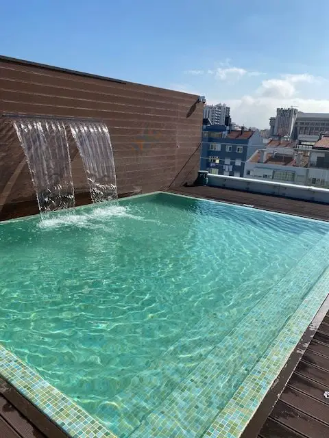 Smaller pool with a waterfall on the rooftop of Lisbon's Hotel Jupiter