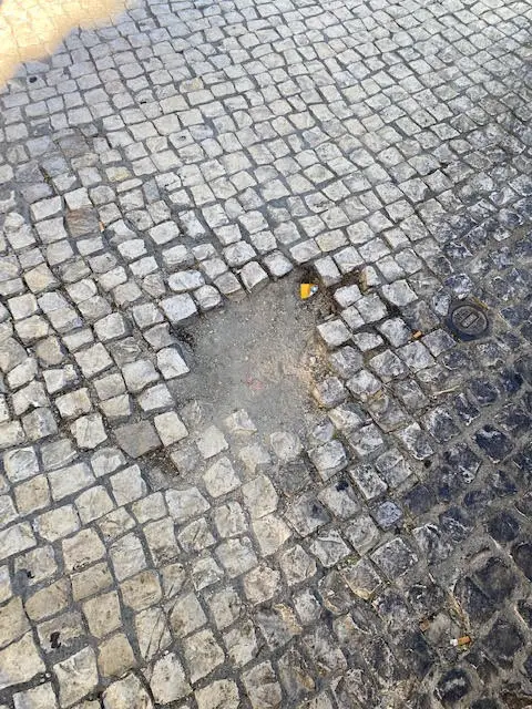 A Portuguese pothole.  Missing cobblestones on a Lisbon, Portugal sidewalk 
