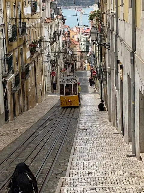 Ascensor da Bica climbing Avenida Duarte Belo on its approach to Largo da Calhariz, Lisbon.  View of Tejo River at the bottom of the hill.
