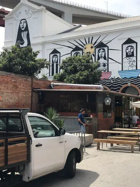 Outdoor restaurant seating below a mural at Lisbon's LX Factory