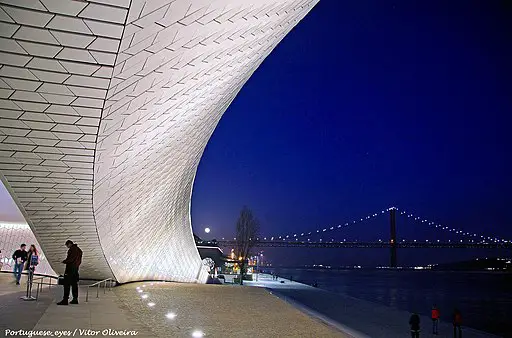 Lisbon's Museum of Art, Architecture, and Technology (MAAT), with 25 April Bridge in the background.  Seen at night.