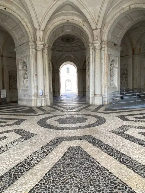 Portico of the Ajuda National Palace, with it's black and white tiled mosaic floor, arched doorways, and statues representing the virtues