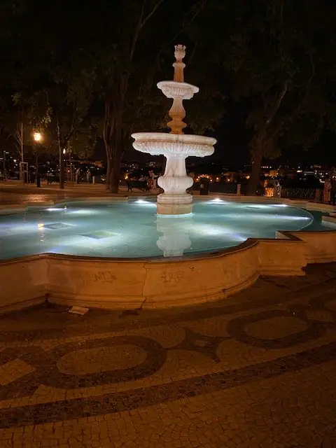 The fountain at Sao Pedro de Alcantara viewpoint in Lisbon lit up at night