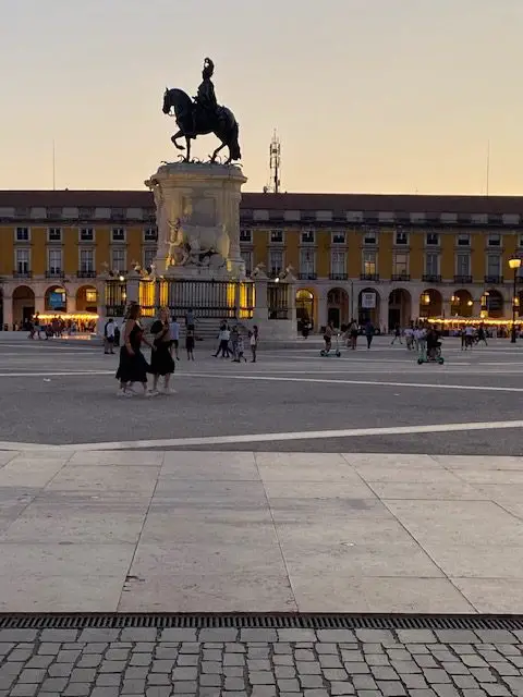 Statue of Dom José I atop his horse in Lisbon's Praça do Comércio.  It is dusk and the building in the background is glowing in light.
