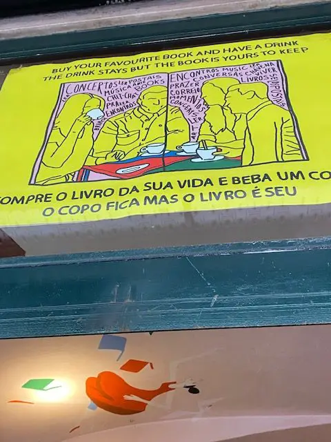 A sign above the door at Lisbon's Bar Menino e Moça explains how the bookshop / bar concept works
