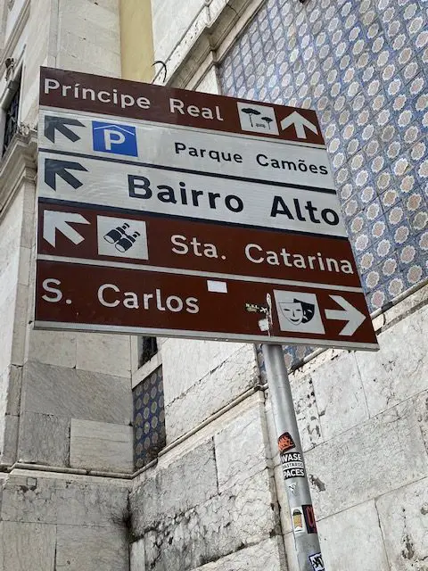 Street sign at Lisbon's Praça Luíis de Camões indicating the direction of Bairro Alto, Principe Real, Santa Catarina viewpoint, and other attractions