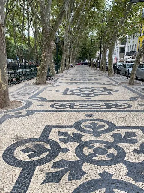 Black and white tiled mosaic sidewalk (known as calçada portuguesa) on the beautiful tree-lined Avenida da Liberdade in Lisbon