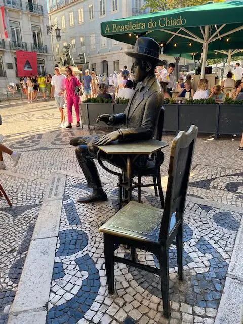 Statue of poet Fernando Pessoa, seated in front of Cafe A Brasileira, in Lisbon, and an empty seat for you.