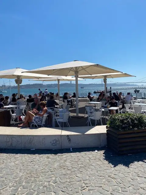 Shaded seating at the riverside Ribeira das Naus kiosk in Lisbon, Portugal.  Enjoying a sunny summer day on the Tejo River.