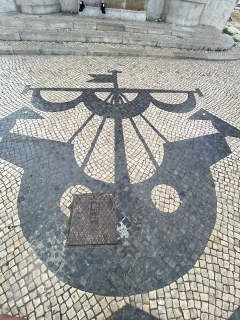 Black and white cobblestone mosaic of a caravel and crows on Lisbon's Avenida Almirante Reis