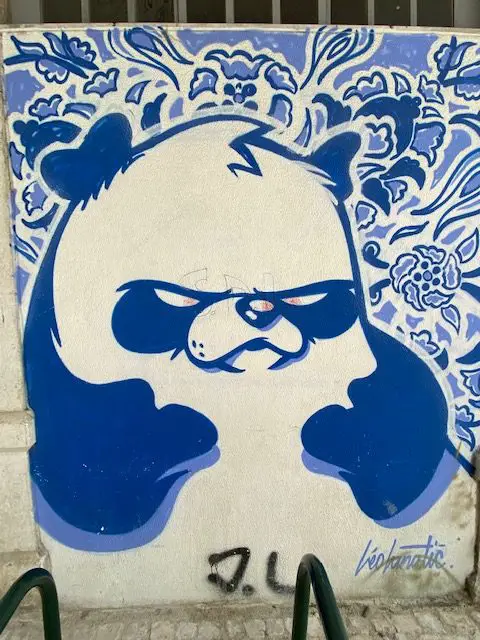 This mural of a large blue and white panda bear with a floral background is by muralist Léo Lunatic.  It is found near  Santa Engrácia - the National Pantheon of Portugal in Lisbon's Alfama neighborhood.