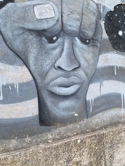 A mural depicting a face in a fist on a wall outside of Lisbon's Fábrica Braço de Prata arts center
