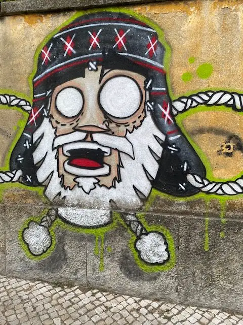 A mural depicting a bearded face and a Himalayan hat outside of Lisbon's Fábrica Braço de Prata arts center