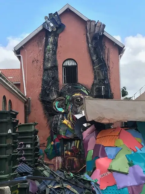 Plastic artist Bordallo II is famous for making large animals out of recycled materials.  Here a giant monkey climbs the wall of his workshop at Rua de Xabregas, 49, Lisbon, Portugal