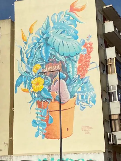 The floral mural Saudade by Mário Belém is found on the side of a building at Rua Damasceno Monteiro, 2 in Lisbon, Portugal