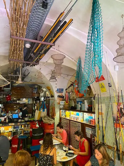The interior of Lisbon's Sol e Pesca is decorated with fishing rods, traps, nets, and other fishing related items