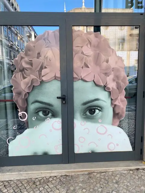 The face of a lady in a spa adorns the glass doors at Lisbon's unique WC Hotel, where the theme is an elegant bathroom and running water